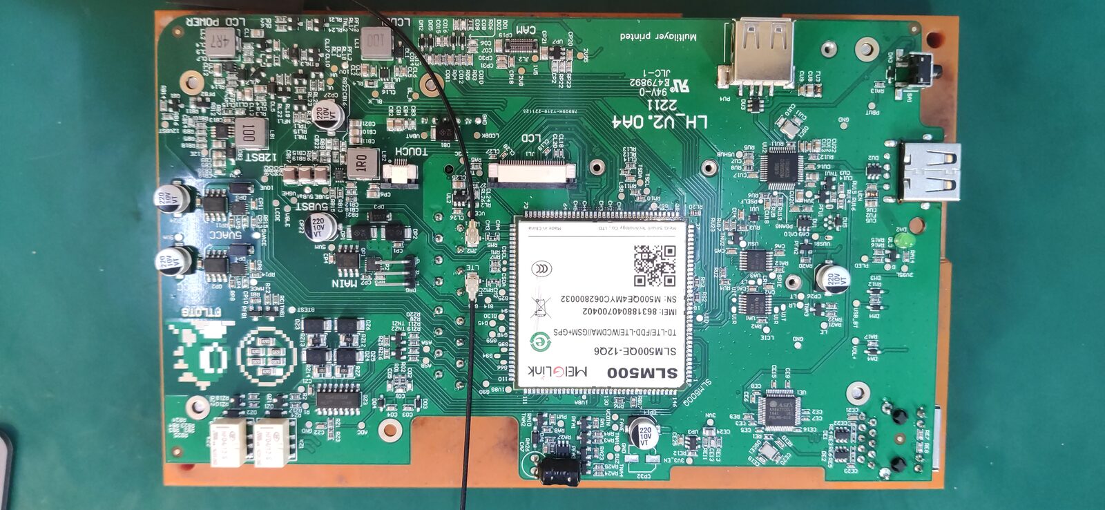 Green circuit board with a labelled module, a USB connector, a micro SD slot and many small components on an orange board holder.